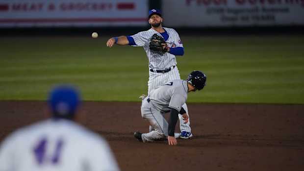 Iowa Cubs second baseman David Bote (13) throws the ball to first baseman Matt Mervis (41) to try and get a double play during the season opener at Principal Park in Des Moines on Friday, March 31, 2023. The Cubs defeated the Clippers, 11-5.